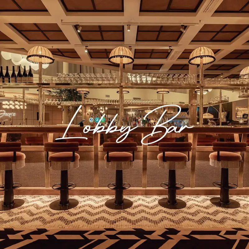 The Lobby Bar counter, lined with velvet stools under fringed pendant lights